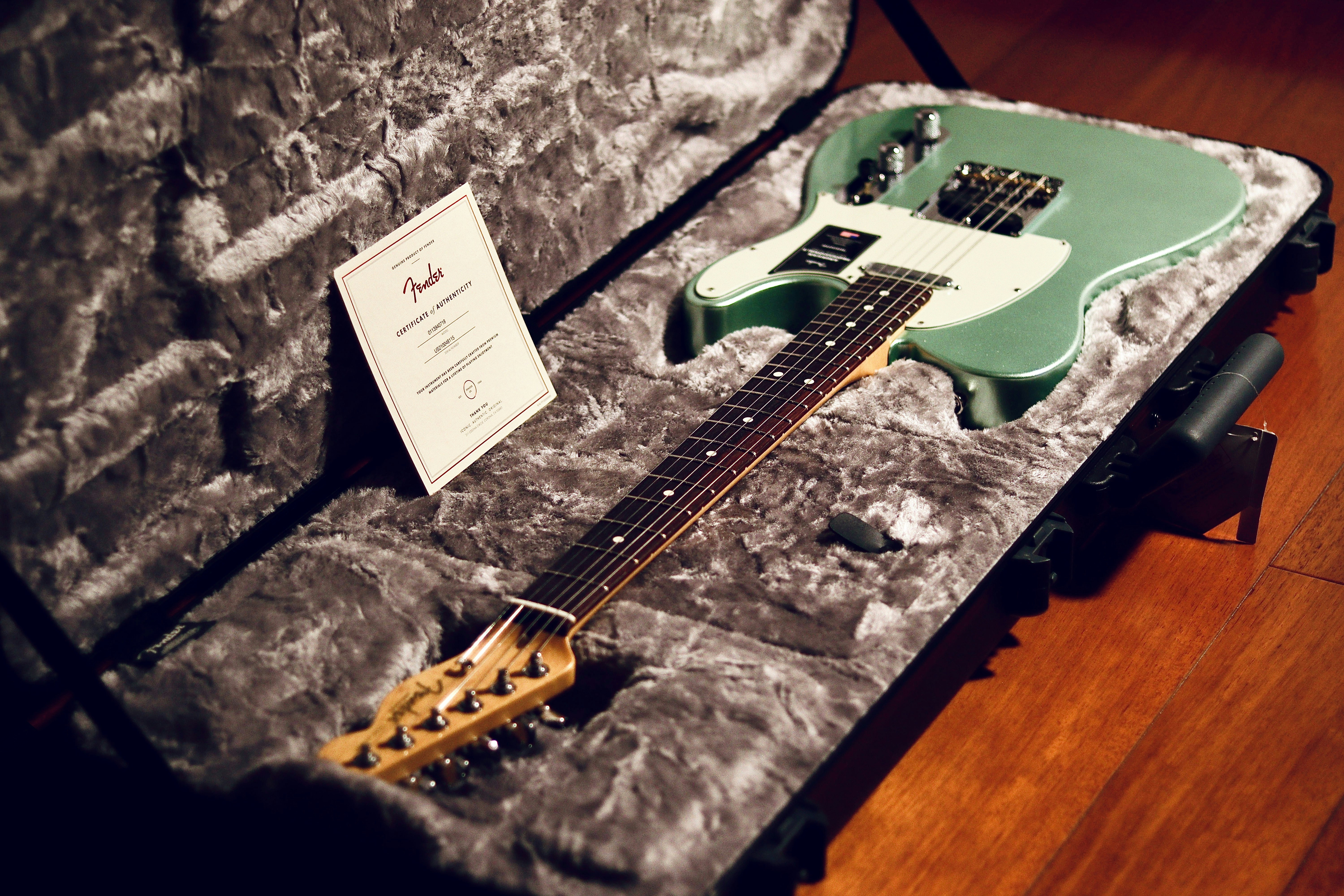 a green electric guitar in a case on a wooden floor