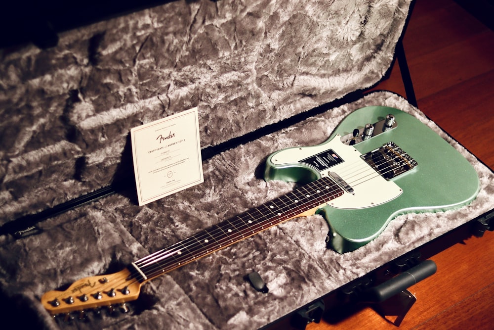 a green electric guitar in a case on a table