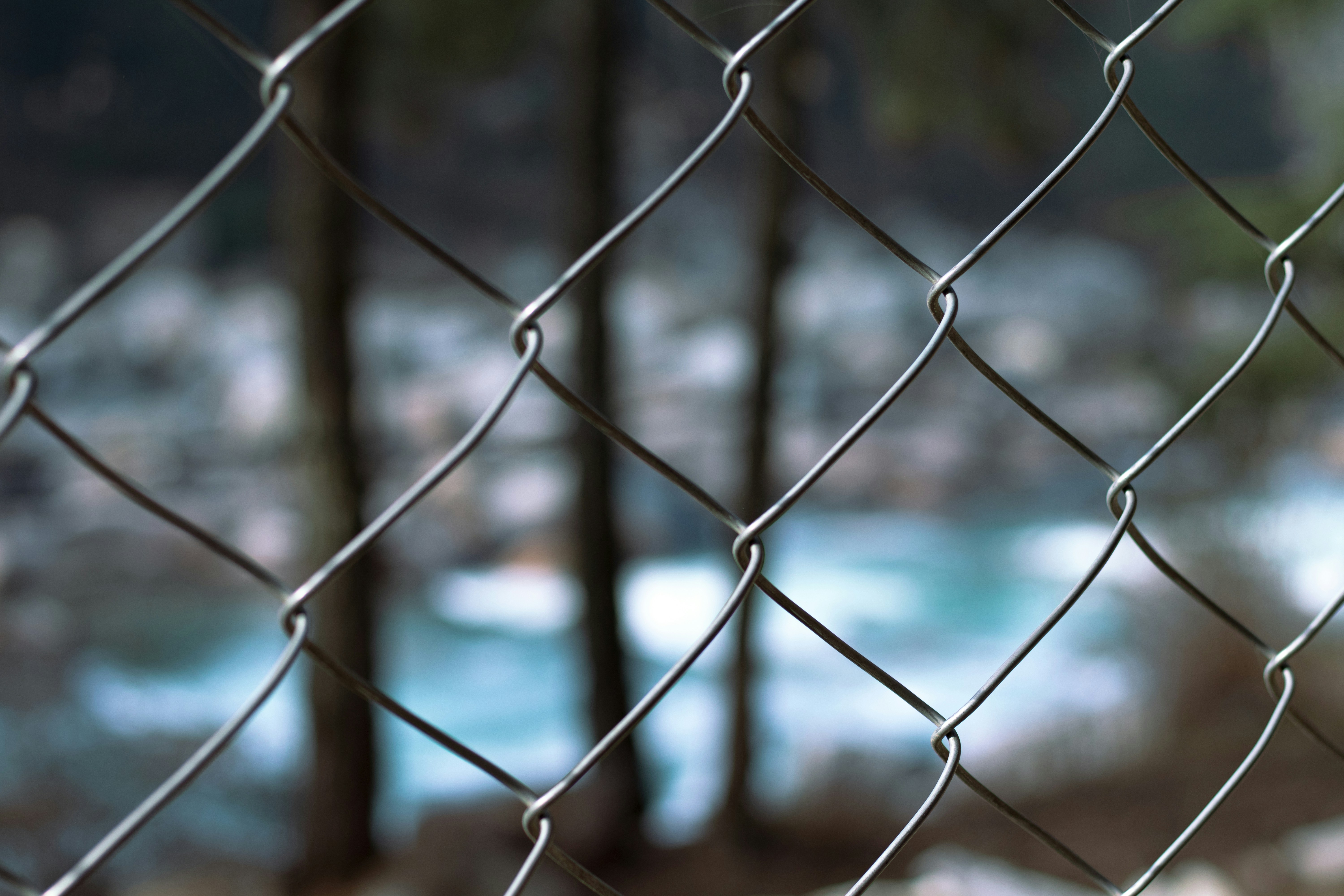 a chain link fence with a river in the background