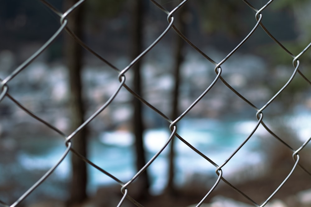 a chain link fence with a river in the background