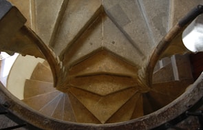 A spiral staircase made of stone winding upwards in natural light.