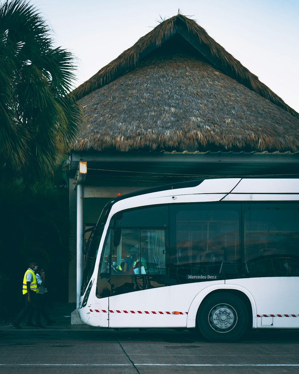 a white bus parked in front of a hut