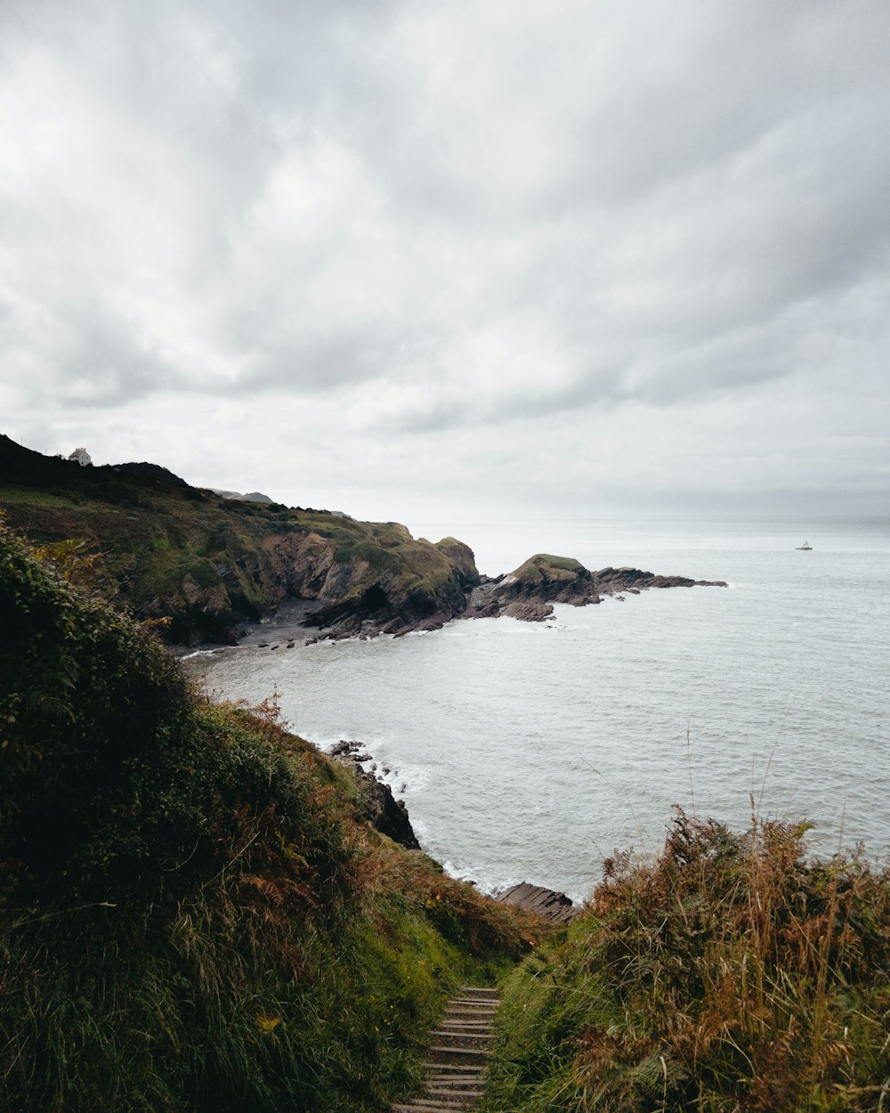 a path leading to the ocean on a cloudy day