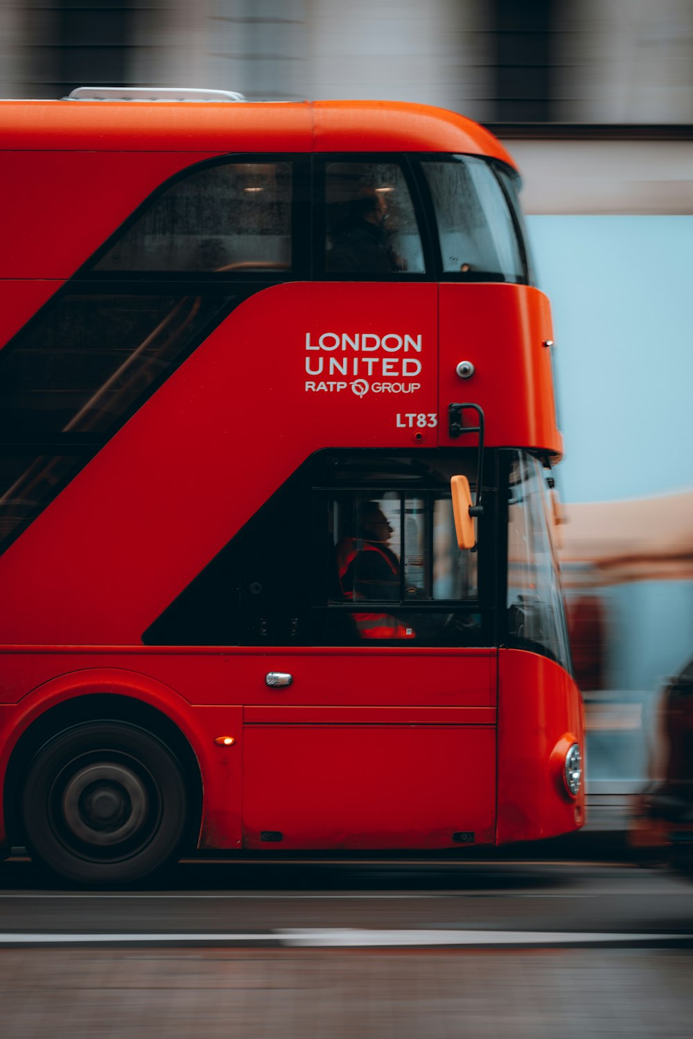 a red double decker bus driving down a street