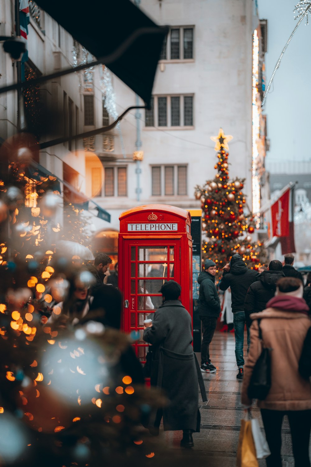 a group of people walking down a street next to a red phone booth