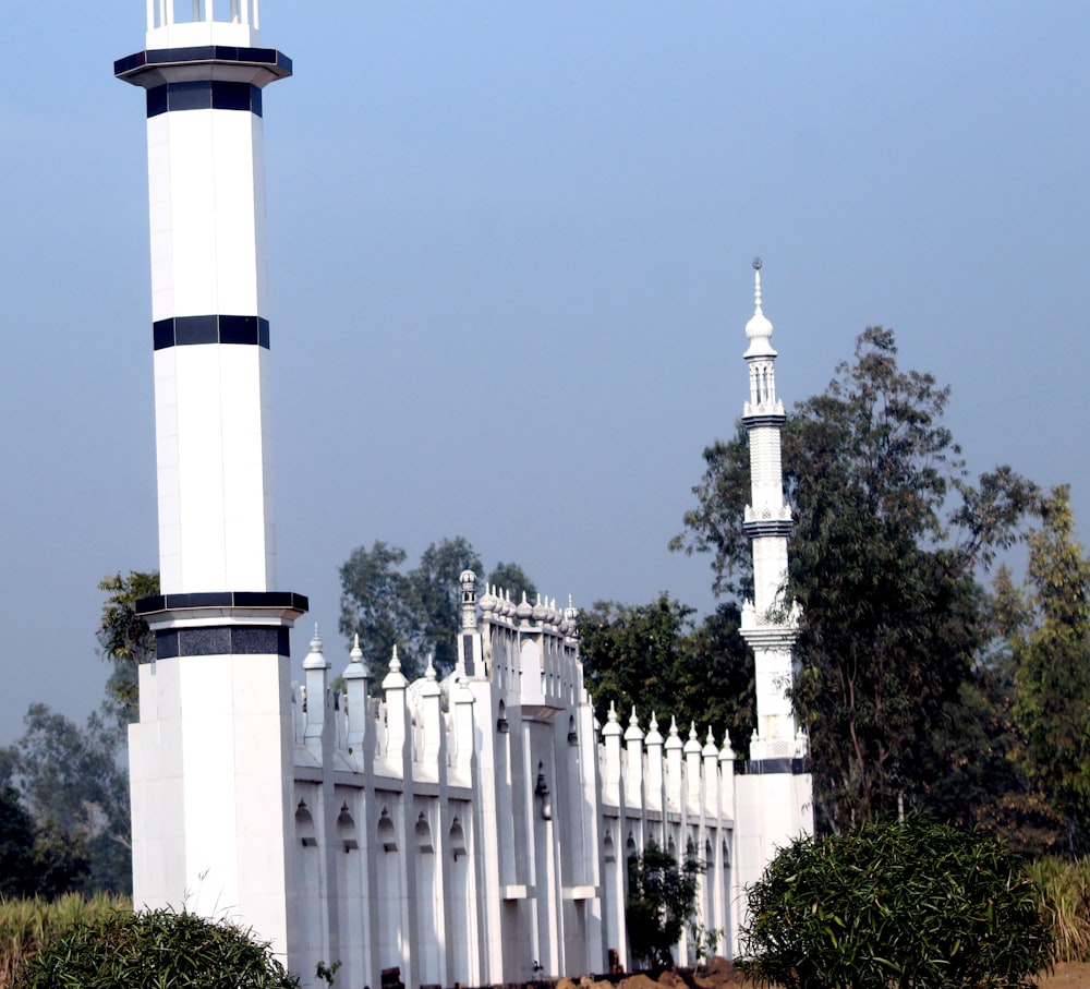 a white and black lighthouse next to a white fence