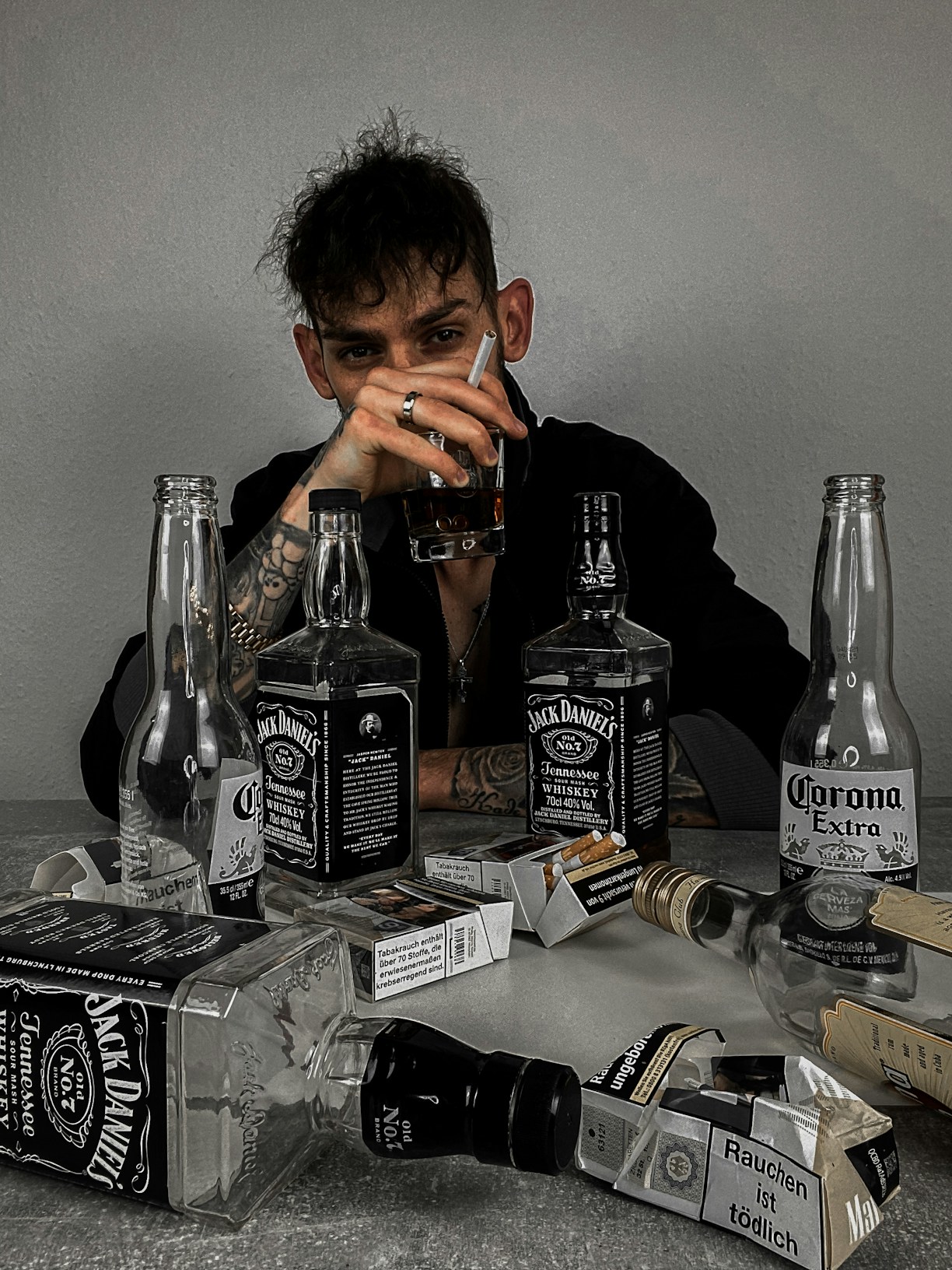 a man sitting at a table with bottles of liquor