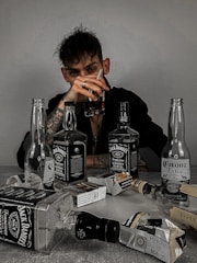 a man sitting at a table with bottles of liquor