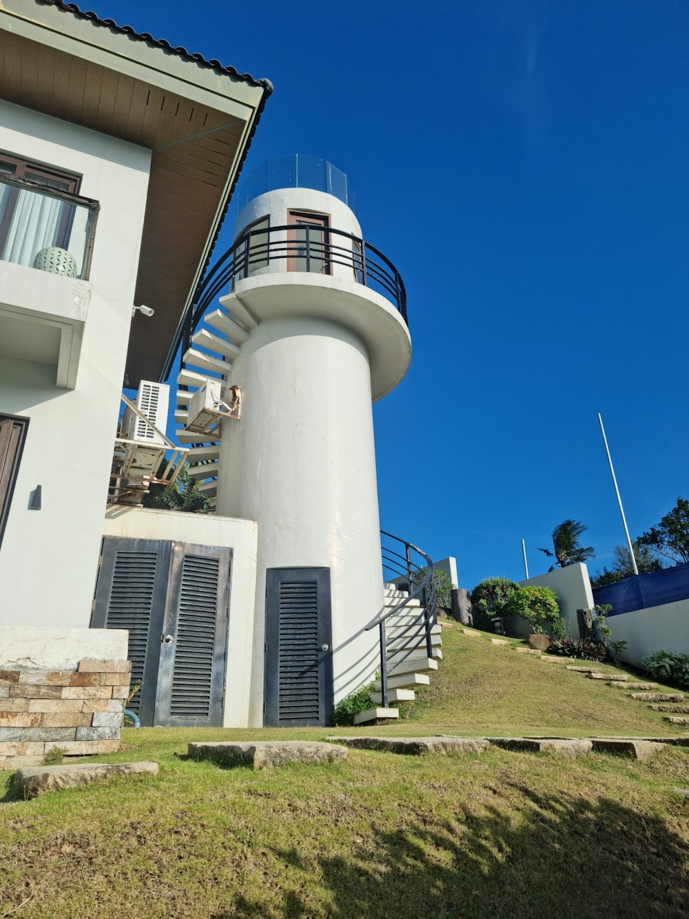 a tall white building with a spiral staircase next to it