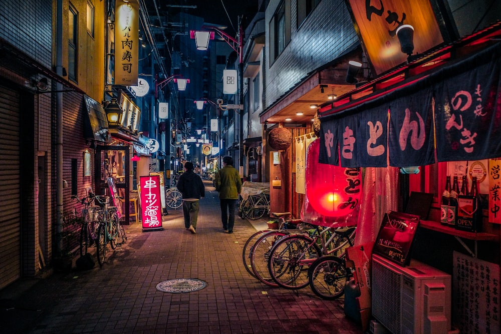 a couple of people walking down a street at night