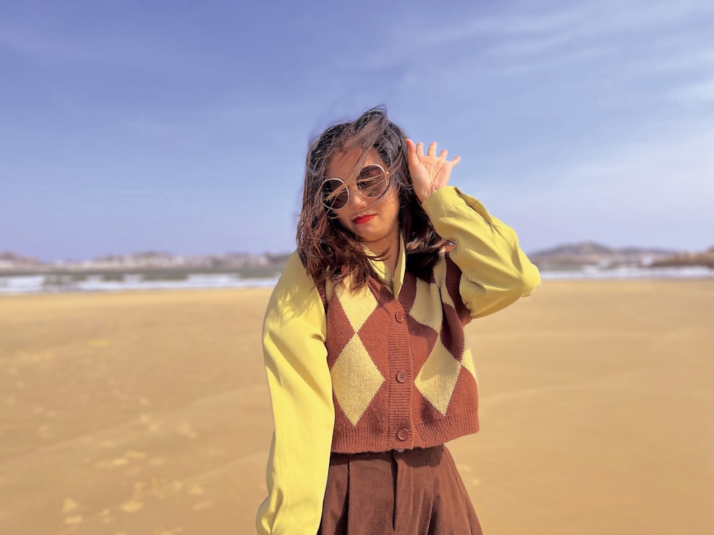 a woman wearing sunglasses and a sweater on a beach