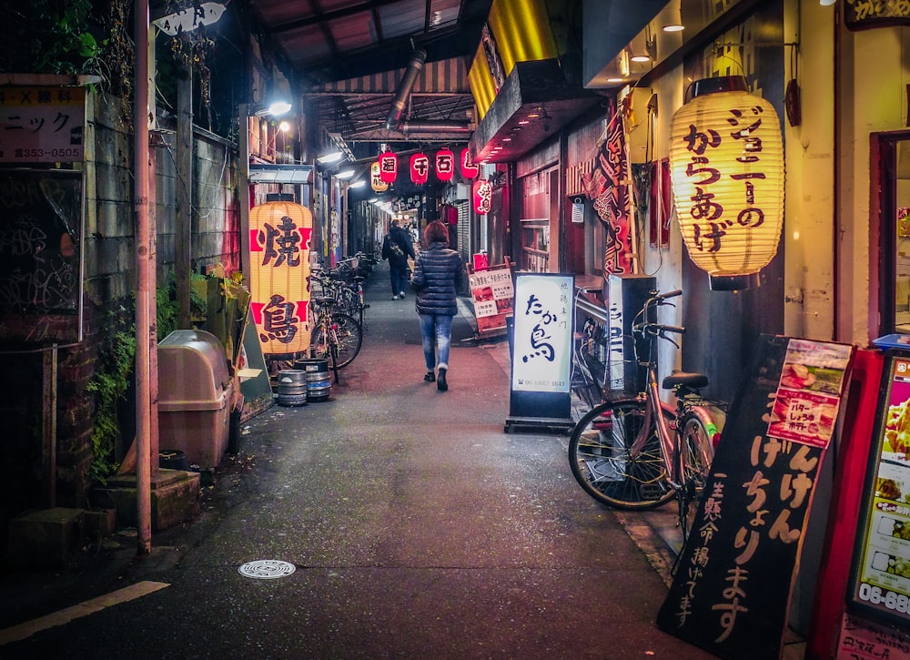 a person walking down a narrow alley way at night