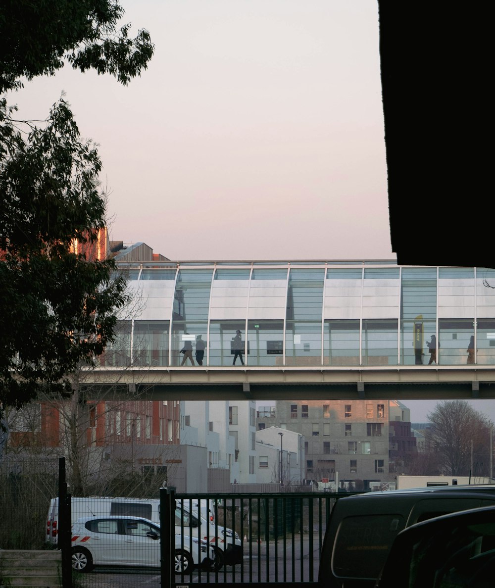 a pedestrian bridge over a city street with cars parked in front of it