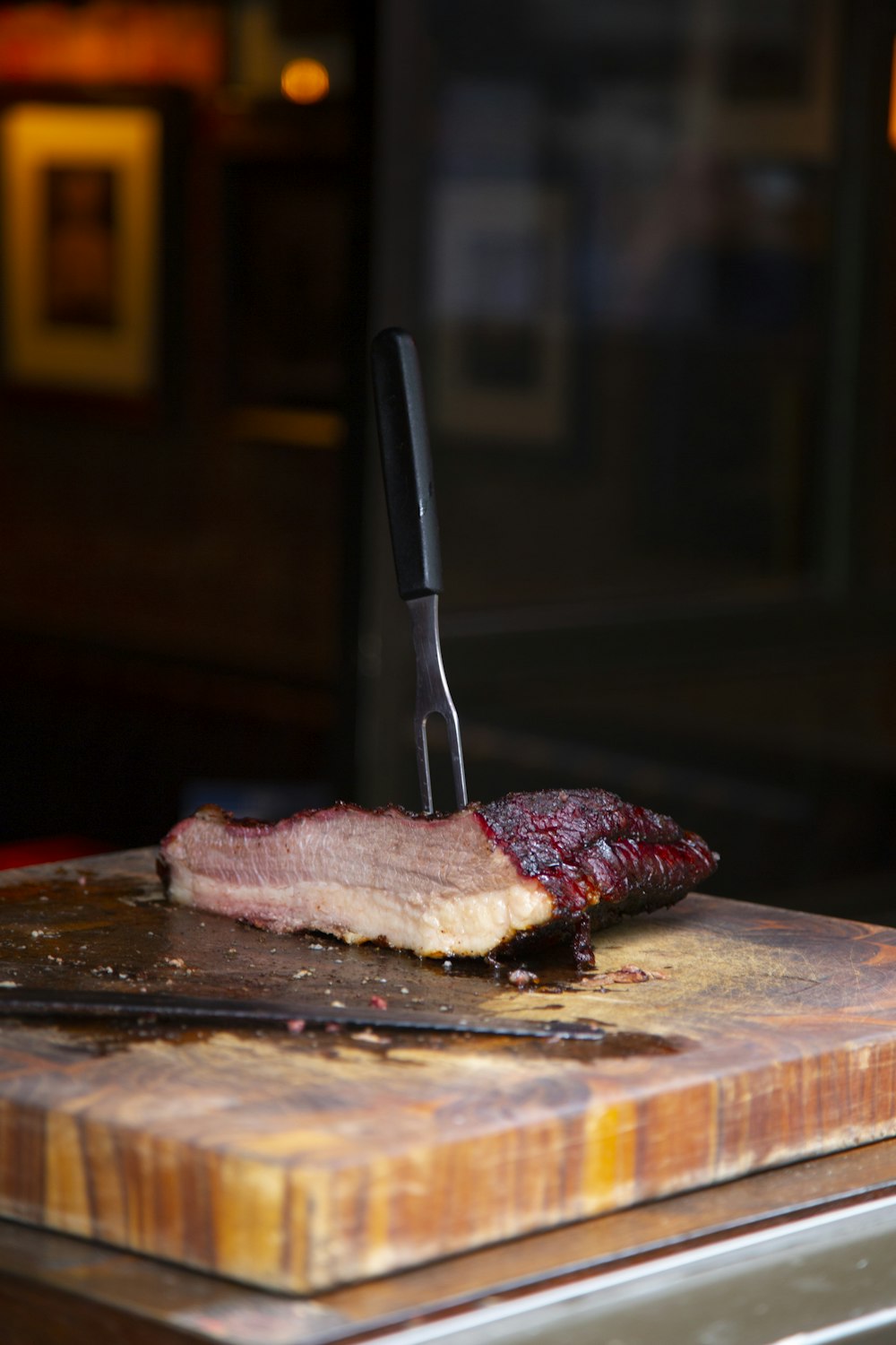 um pedaço de carne em uma tábua de corte com uma faca