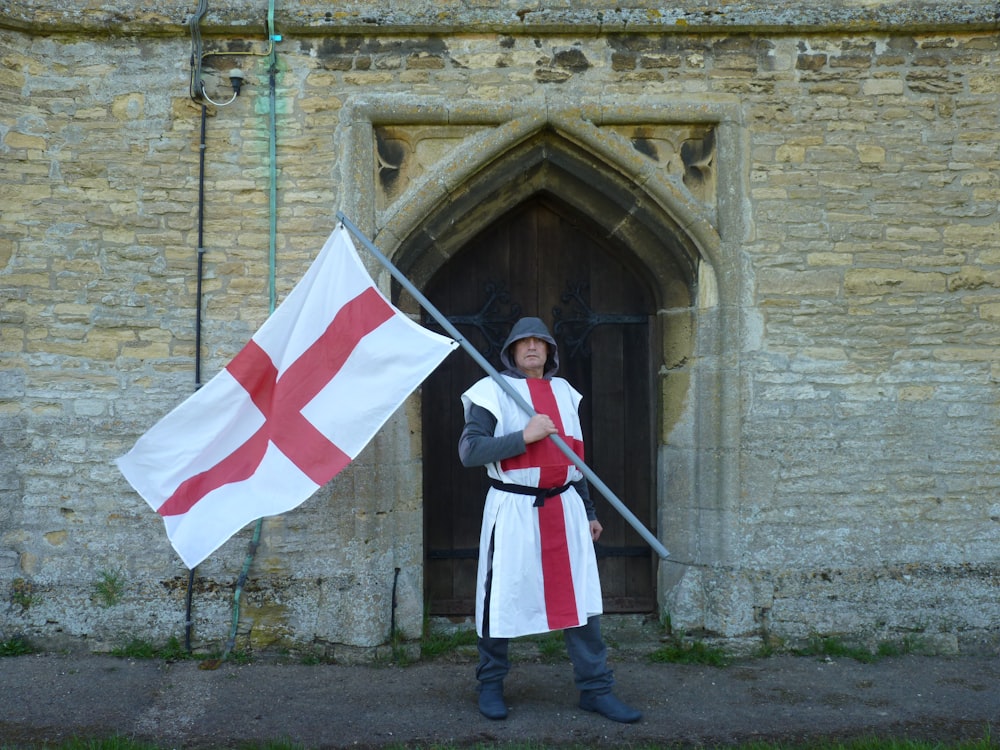 a man holding a flag in front of a stone building