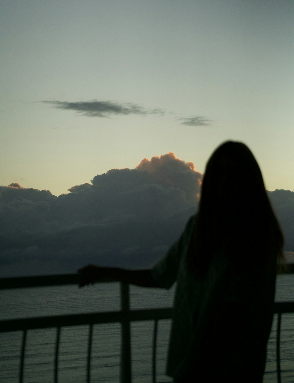 a woman standing on a balcony looking out at the ocean