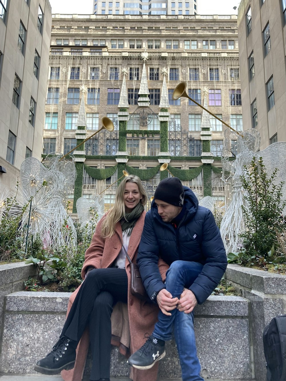 a man and a woman sitting on a bench in front of a building