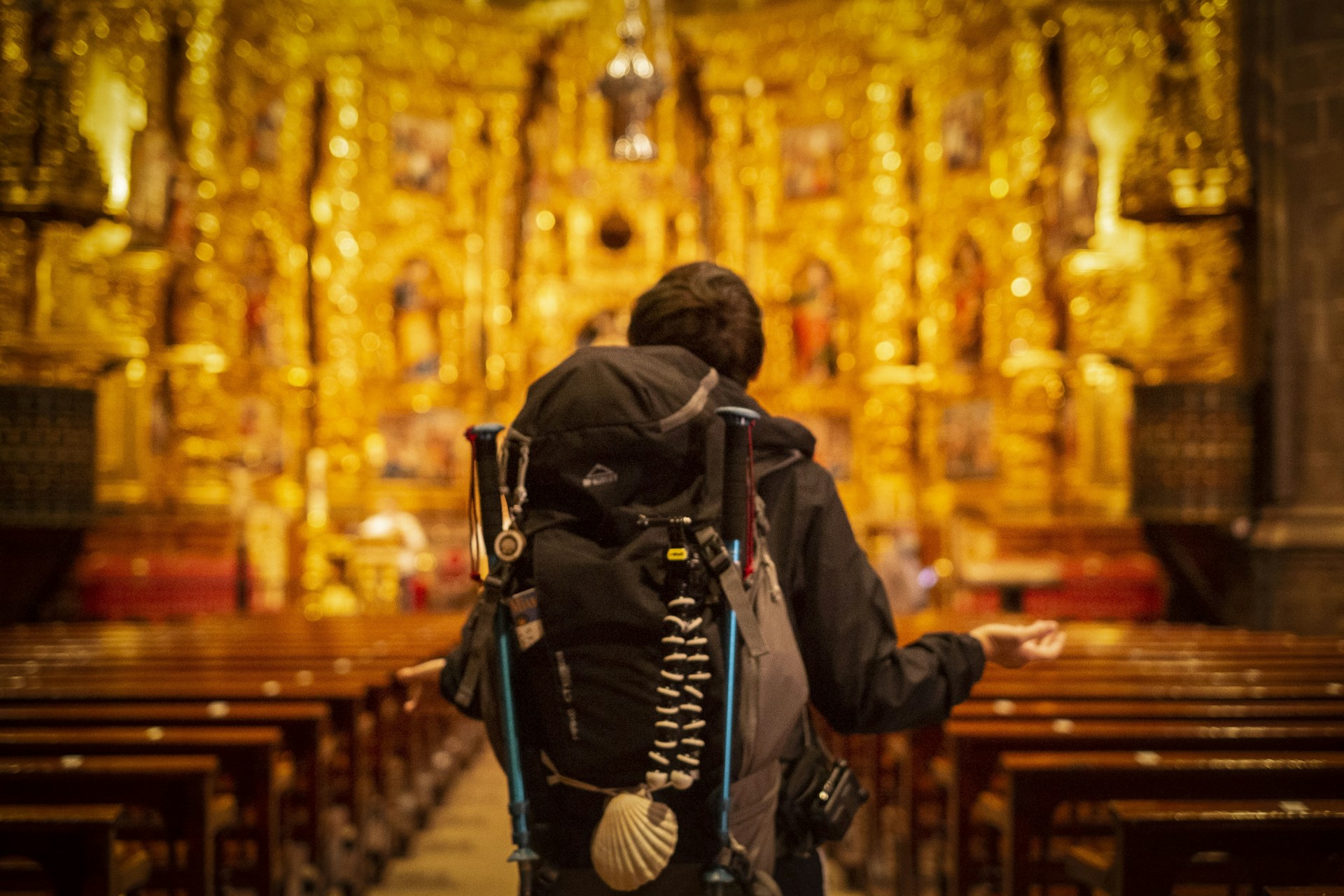 Pilgrim with backpack facing ornate church altar