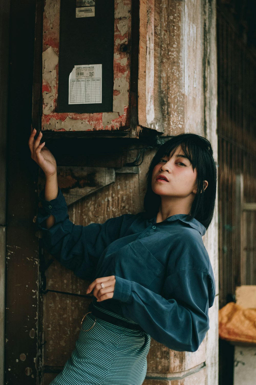 a woman leaning up against a wooden wall