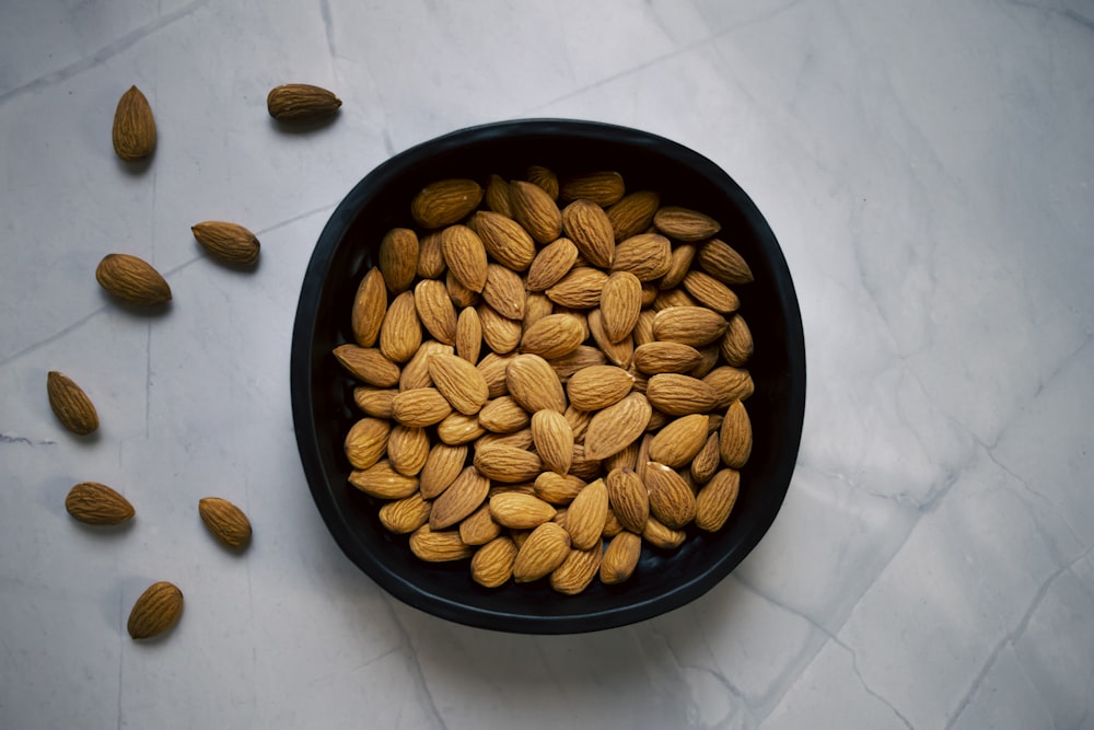 a bowl of almonds on a marble table