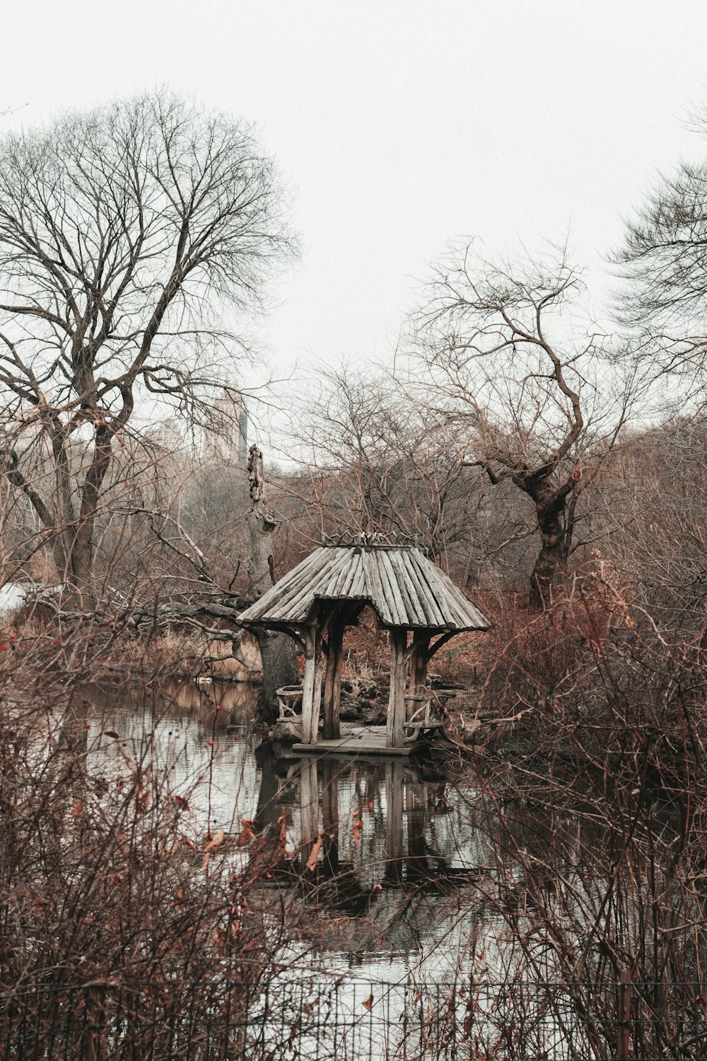 a gazebo in the middle of a pond surrounded by trees