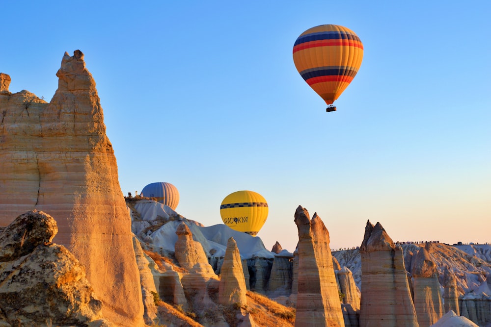 Eine Gruppe von Heißluftballons fliegt über eine felsige Landschaft