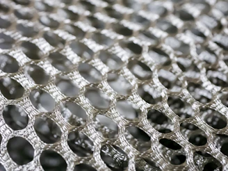 Close-up of a stainless steel filter mesh with fine, precise weaving reflecting light.