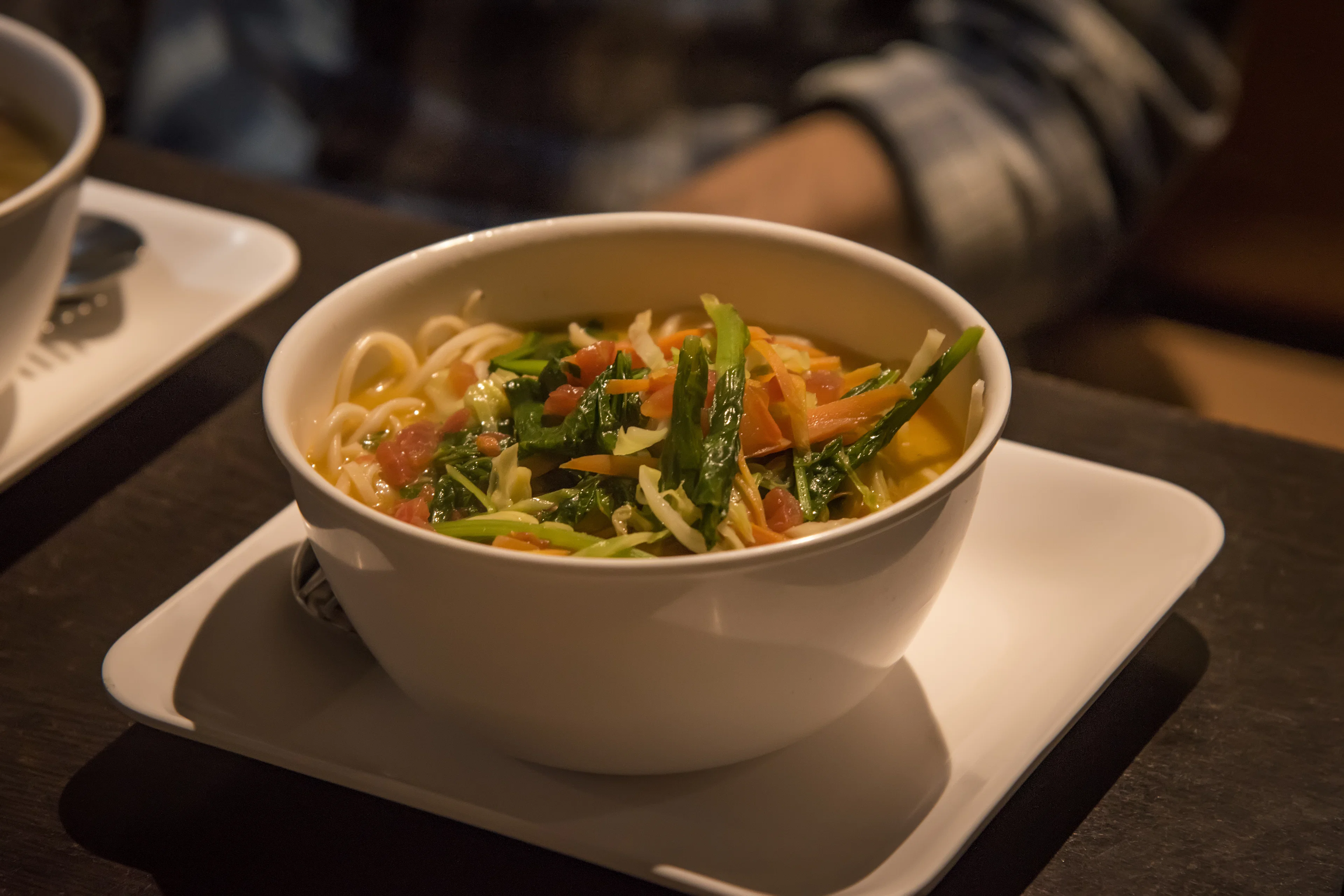 Bowl of thukpa noodle soup with greens, carrot and tomato