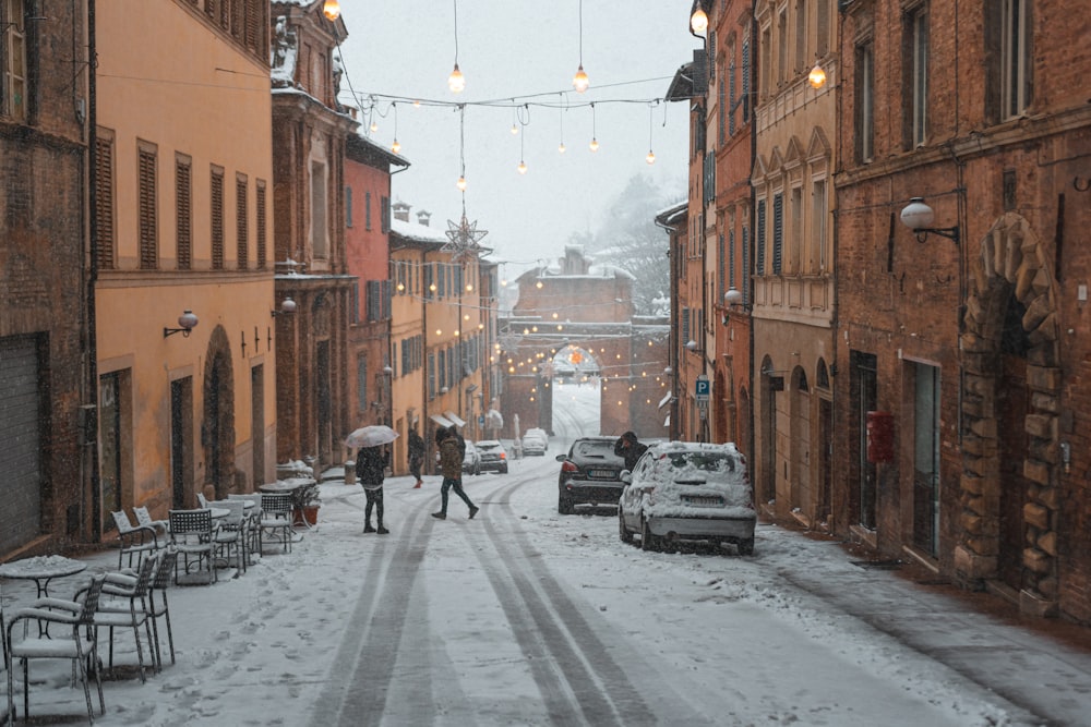 a couple of people walking down a snow covered street