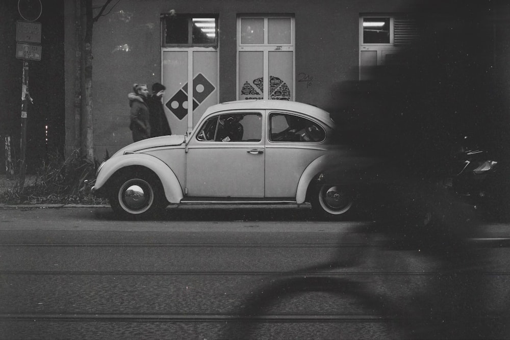 a black and white photo of a car parked in front of a building