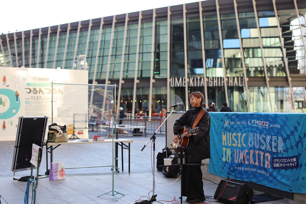 a man playing a guitar in front of a building