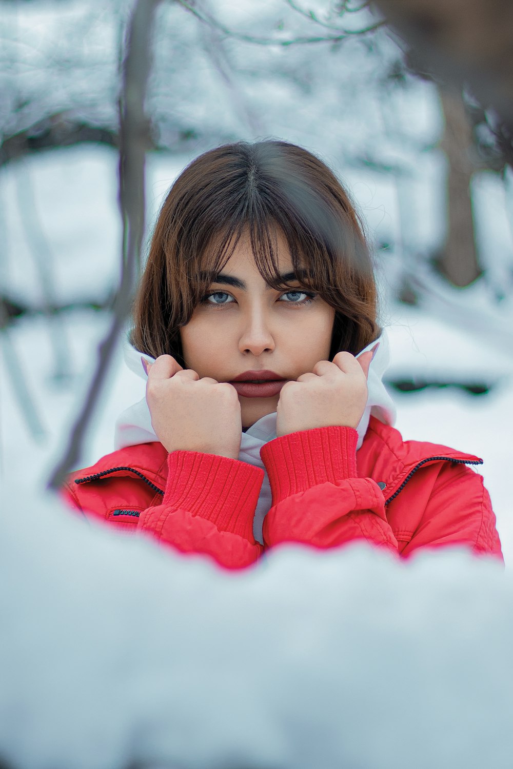 a woman in a red jacket standing in the snow