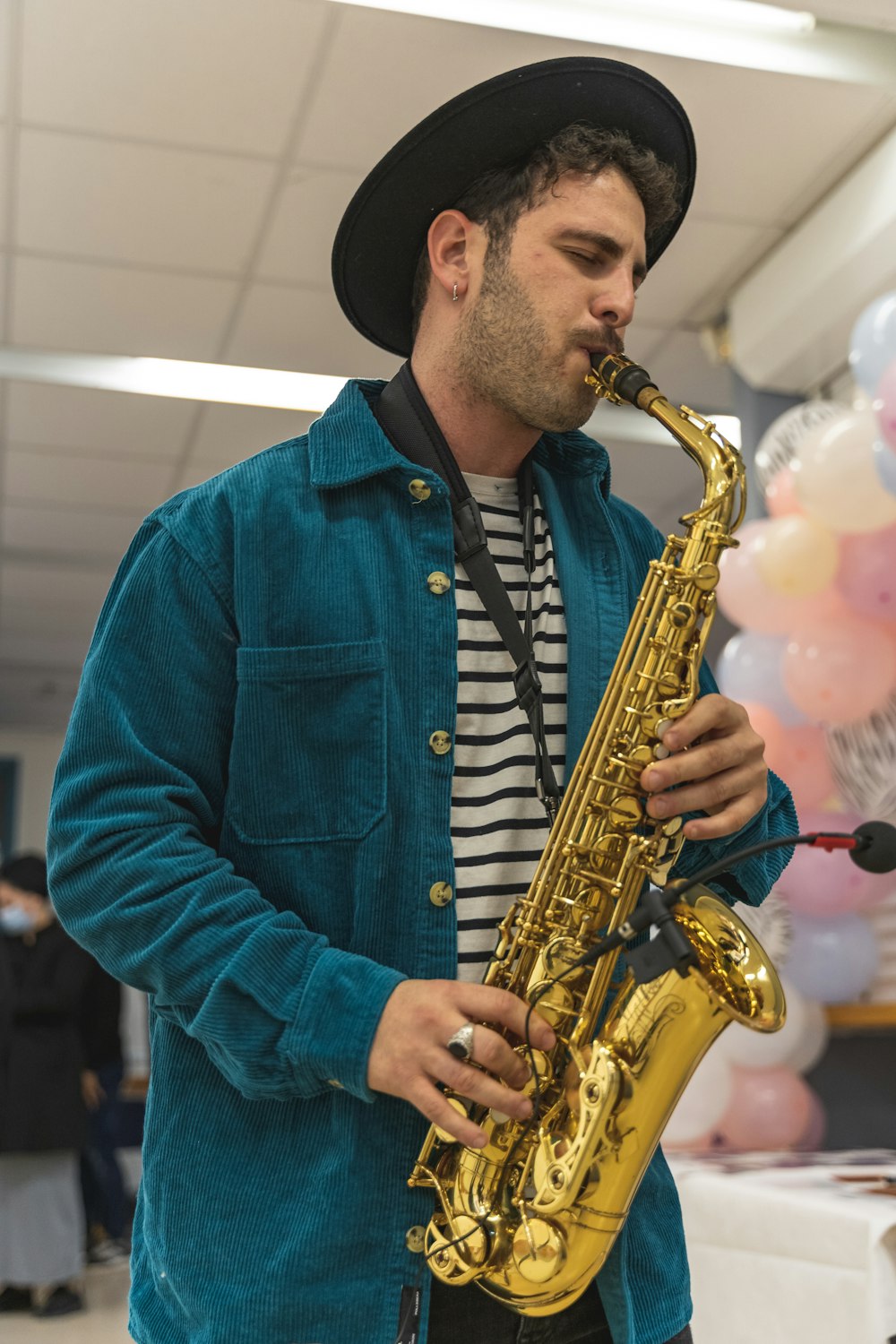 a man in a blue jacket playing a saxophone