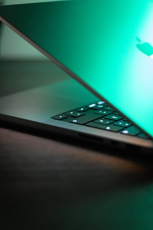 Apple MacBook Pro on a desk with ambient green lighting in a dark workspace