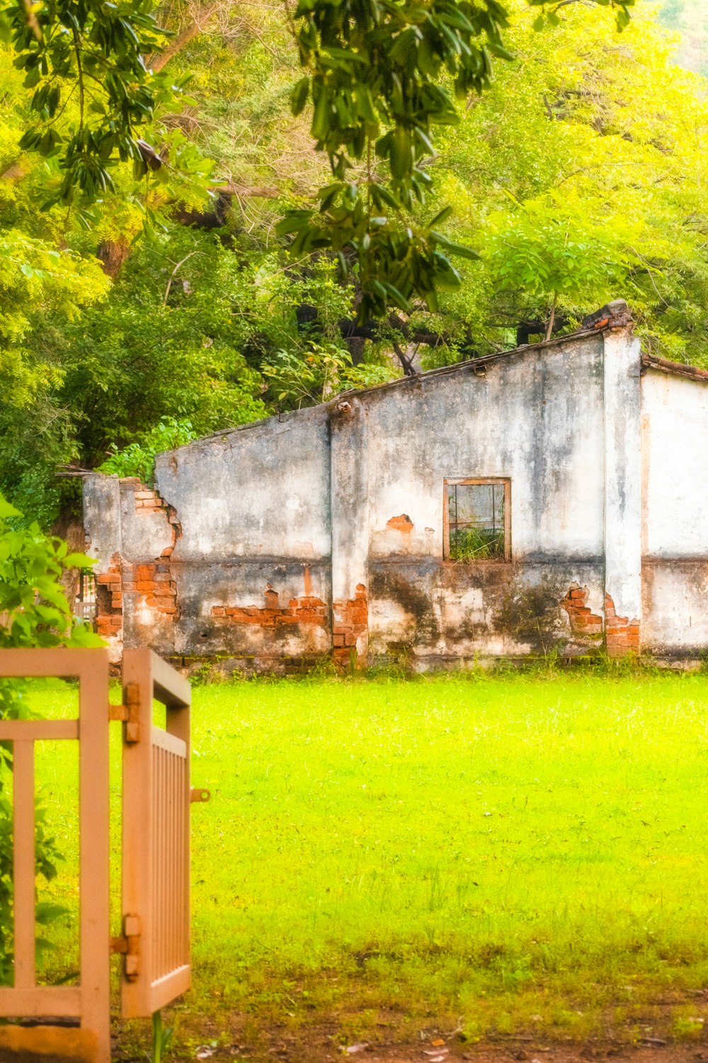 an old building sitting in the middle of a lush green field