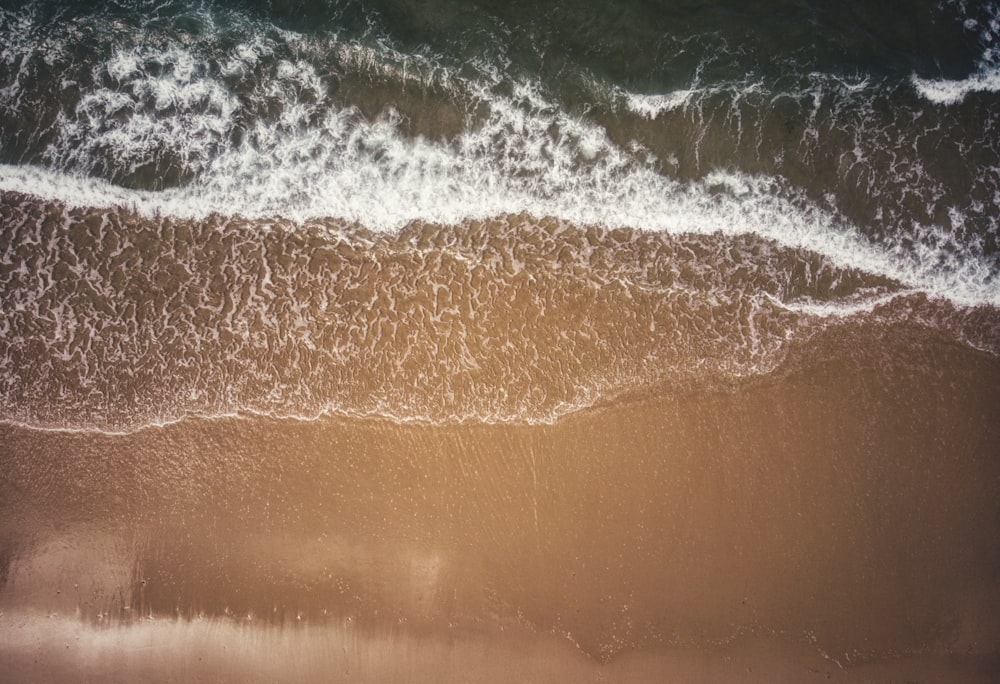 an aerial view of a beach with waves coming in