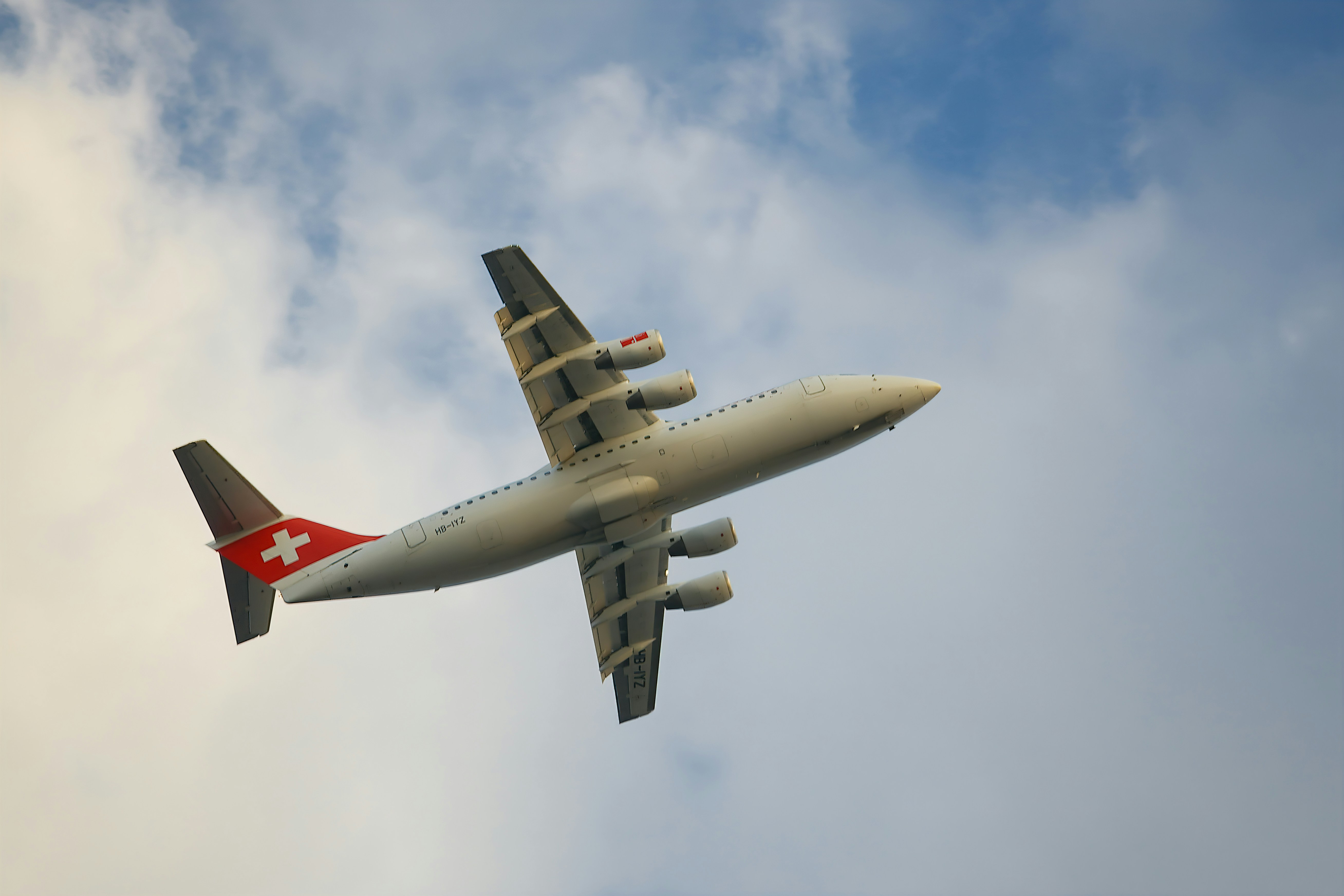 a large passenger jet flying through a cloudy blue sky, Swiss Airlines plane landing at London City Airport.