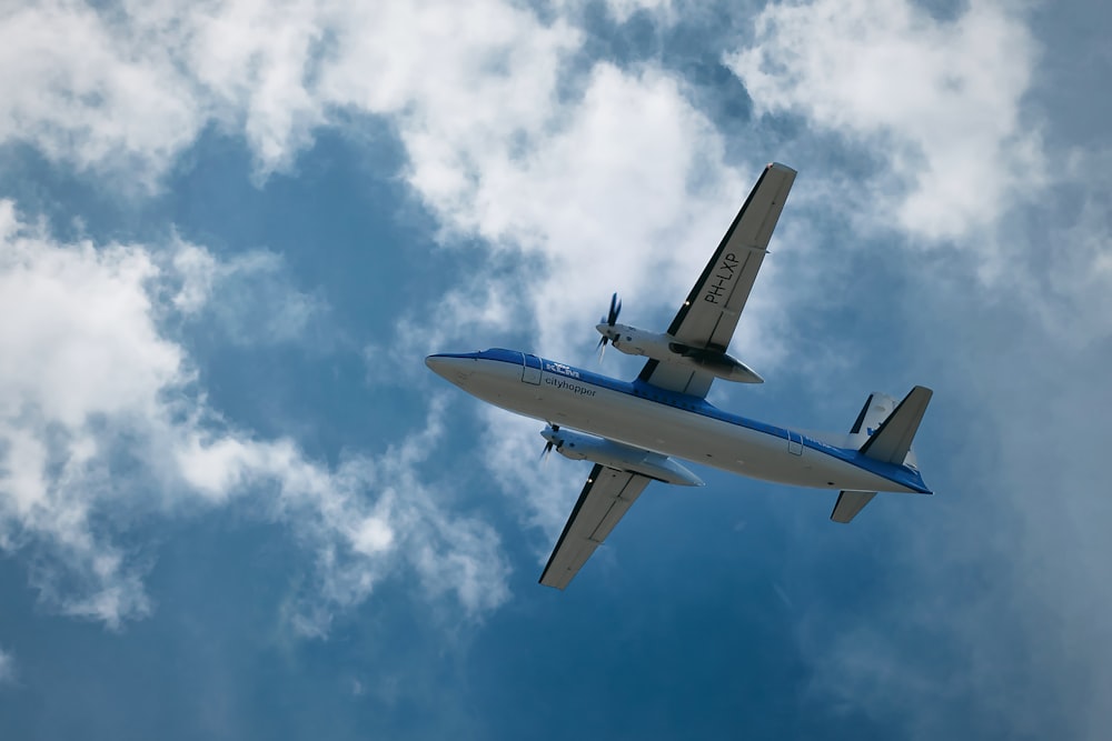 an airplane flying in the sky with clouds in the background