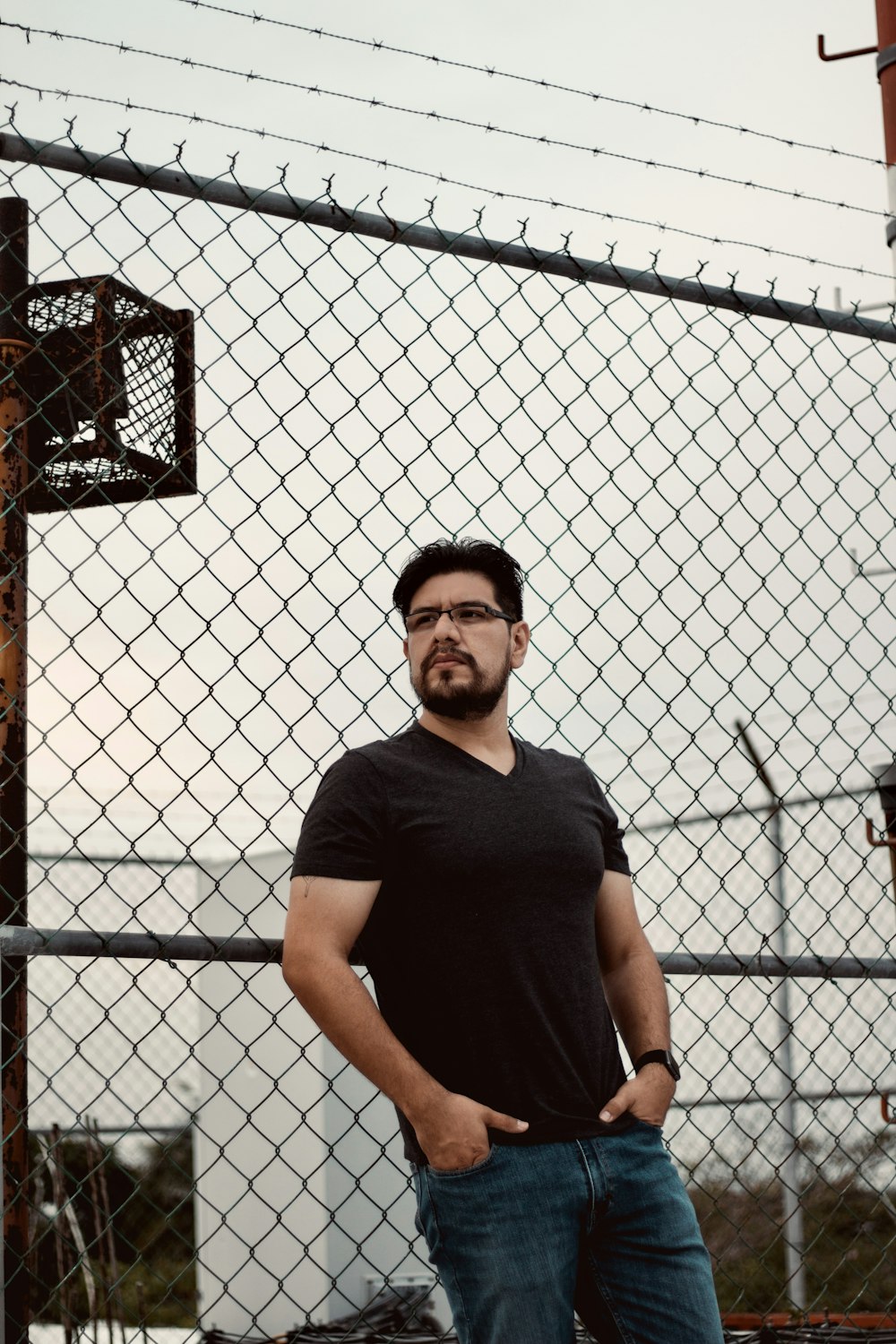 a man standing in front of a chain link fence
