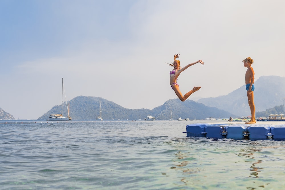 two people jumping off a dock into the water