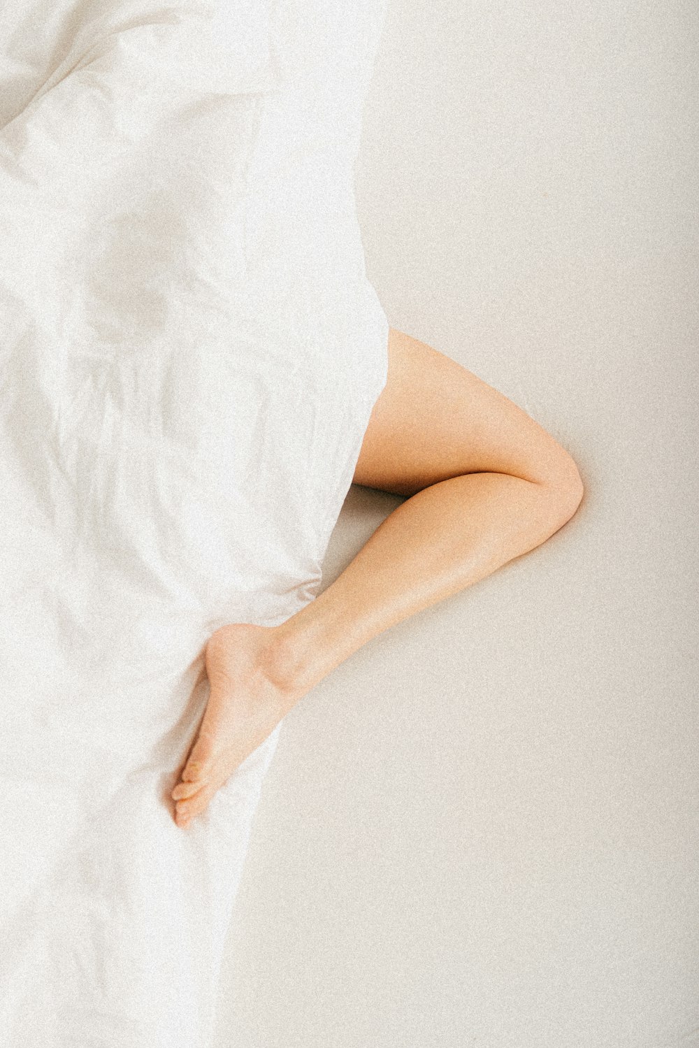 a person laying in a bed with a white sheet
