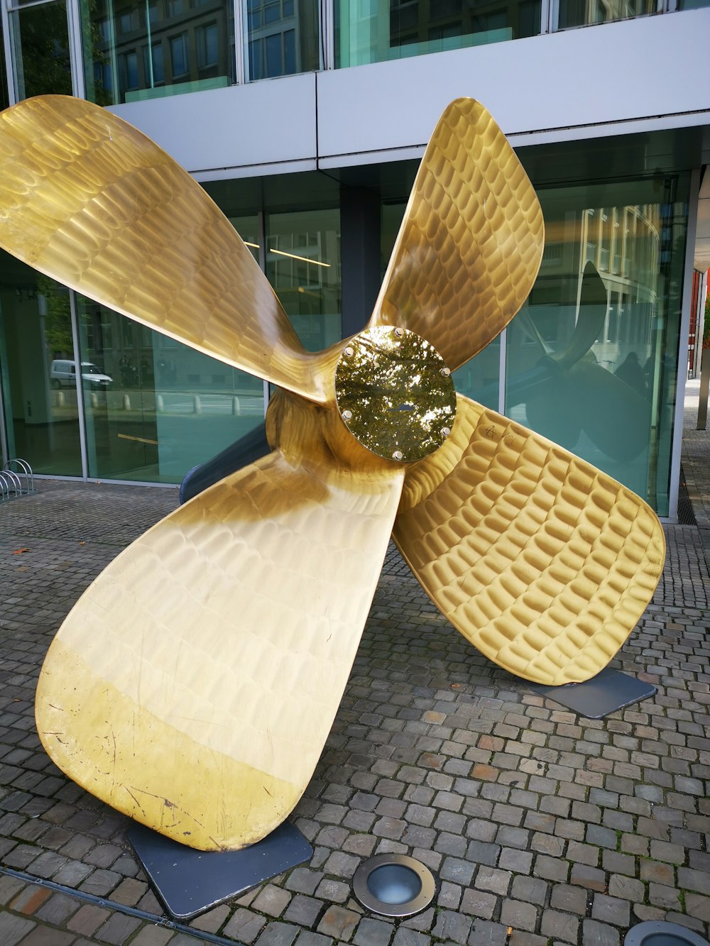 a large metal propeller sitting on top of a sidewalk