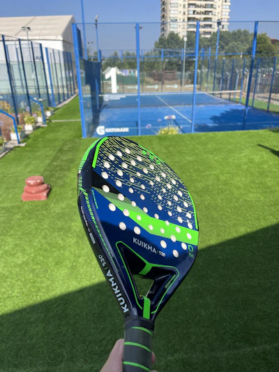A vibrant padel court with a custom blue tarp bearing a club's golden logo.