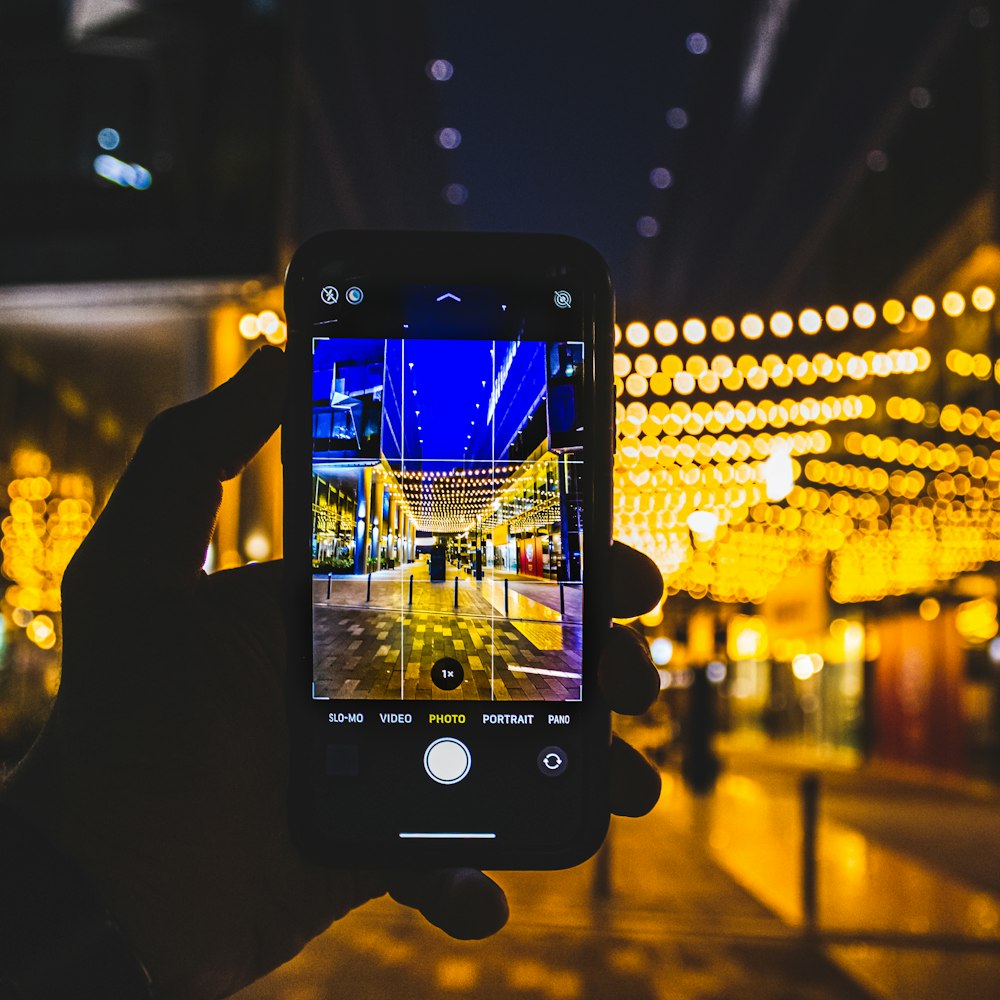 a person taking a picture of a street at night