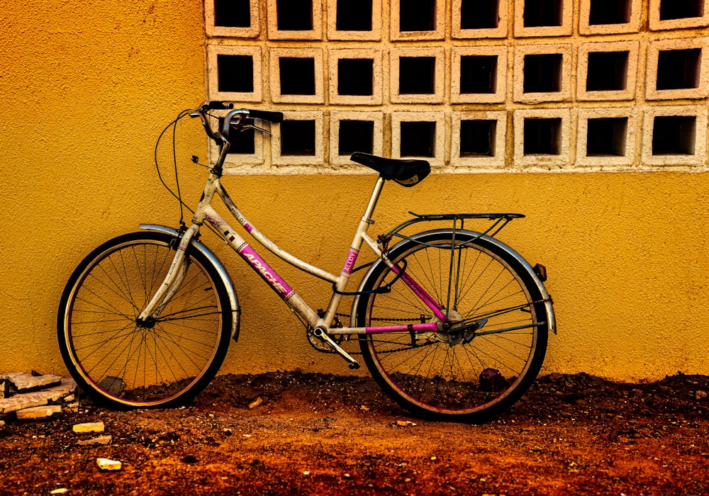 a bike leaning against a yellow wall near a window