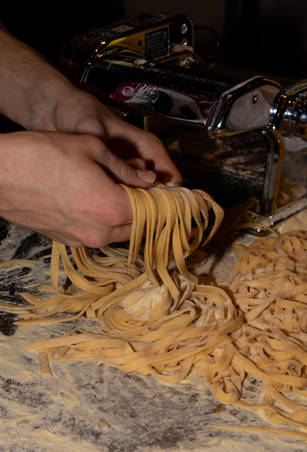 Fresh pasta being rolled through a pasta machine