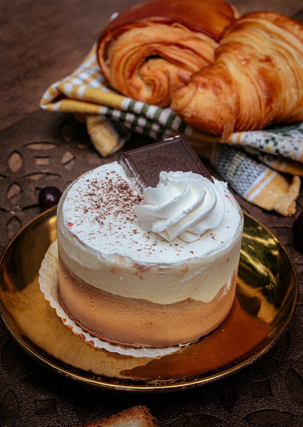 a cake on a plate with a croissant in the background