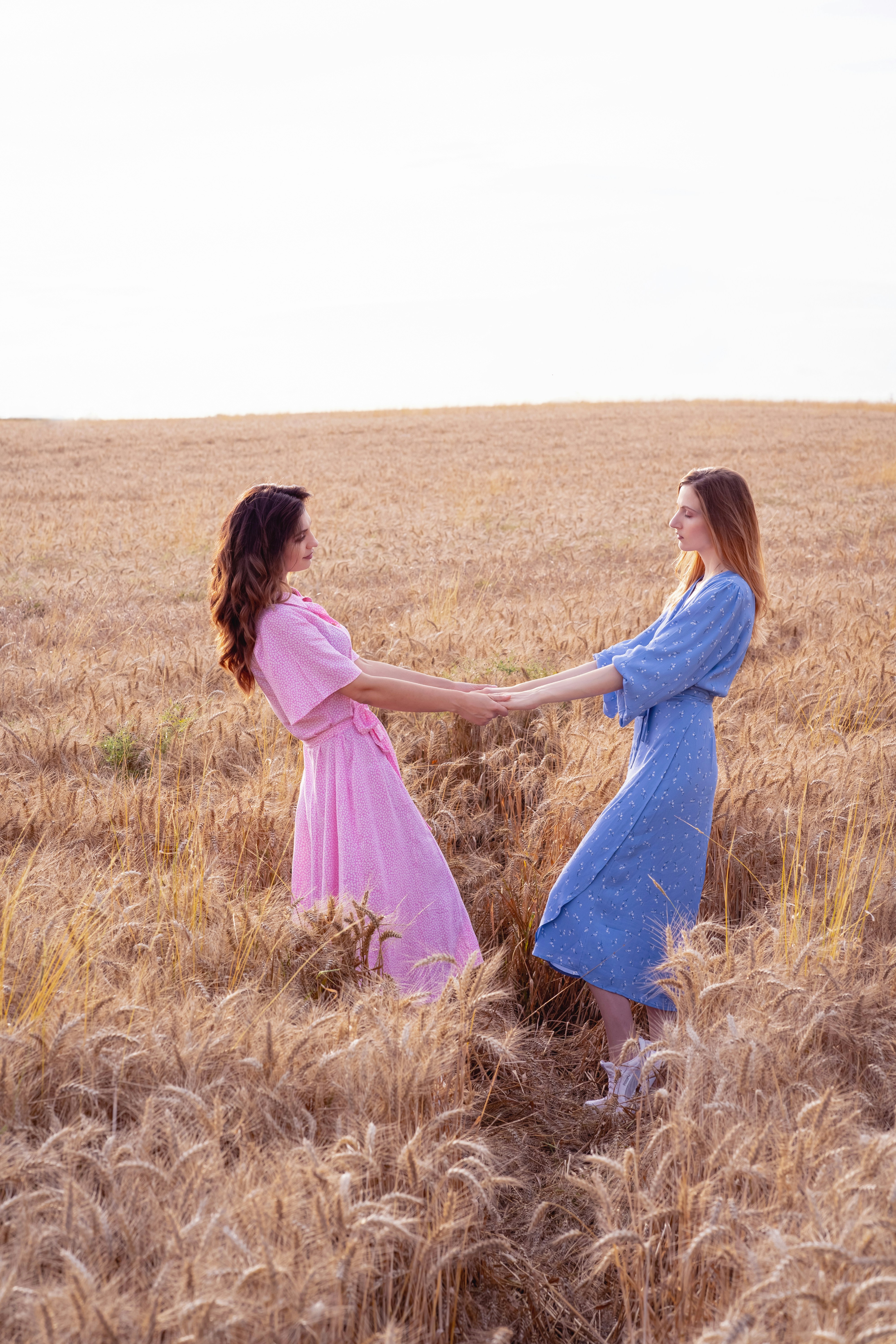 Weimar, Germany - August 2021: two woman in blue dress and woman in pink dress on the wheat field