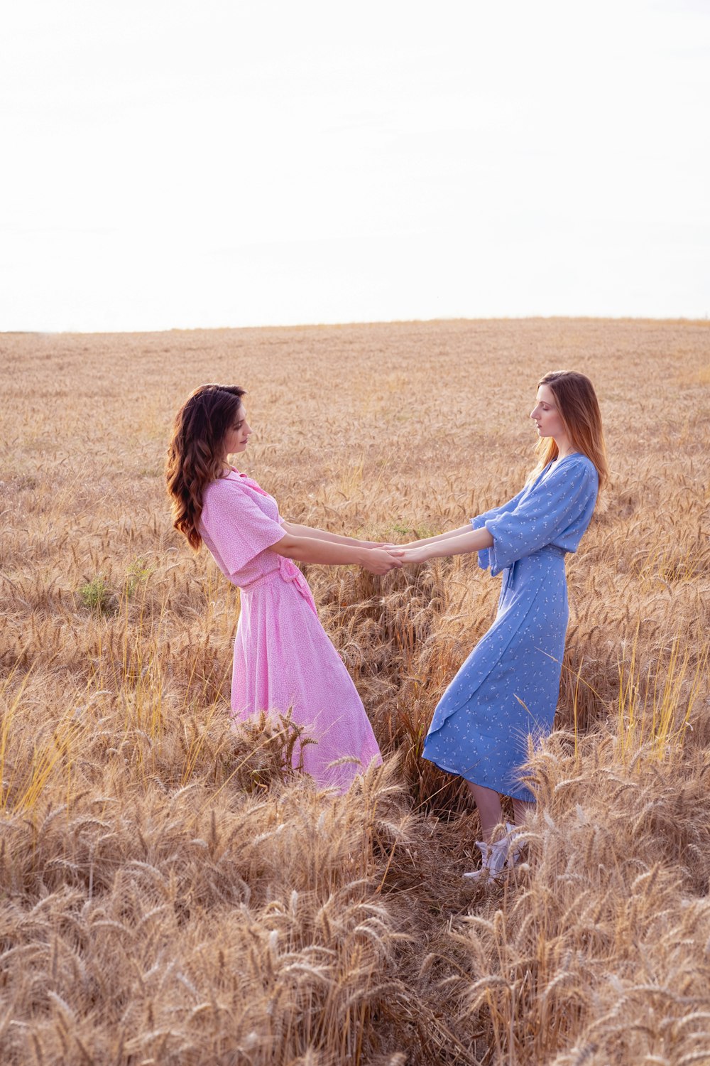 two women in a field holding hands