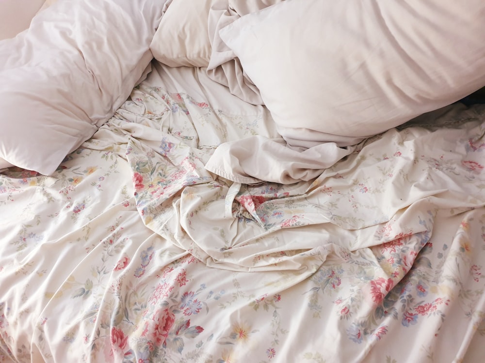 a messy bed with white sheets and pillows